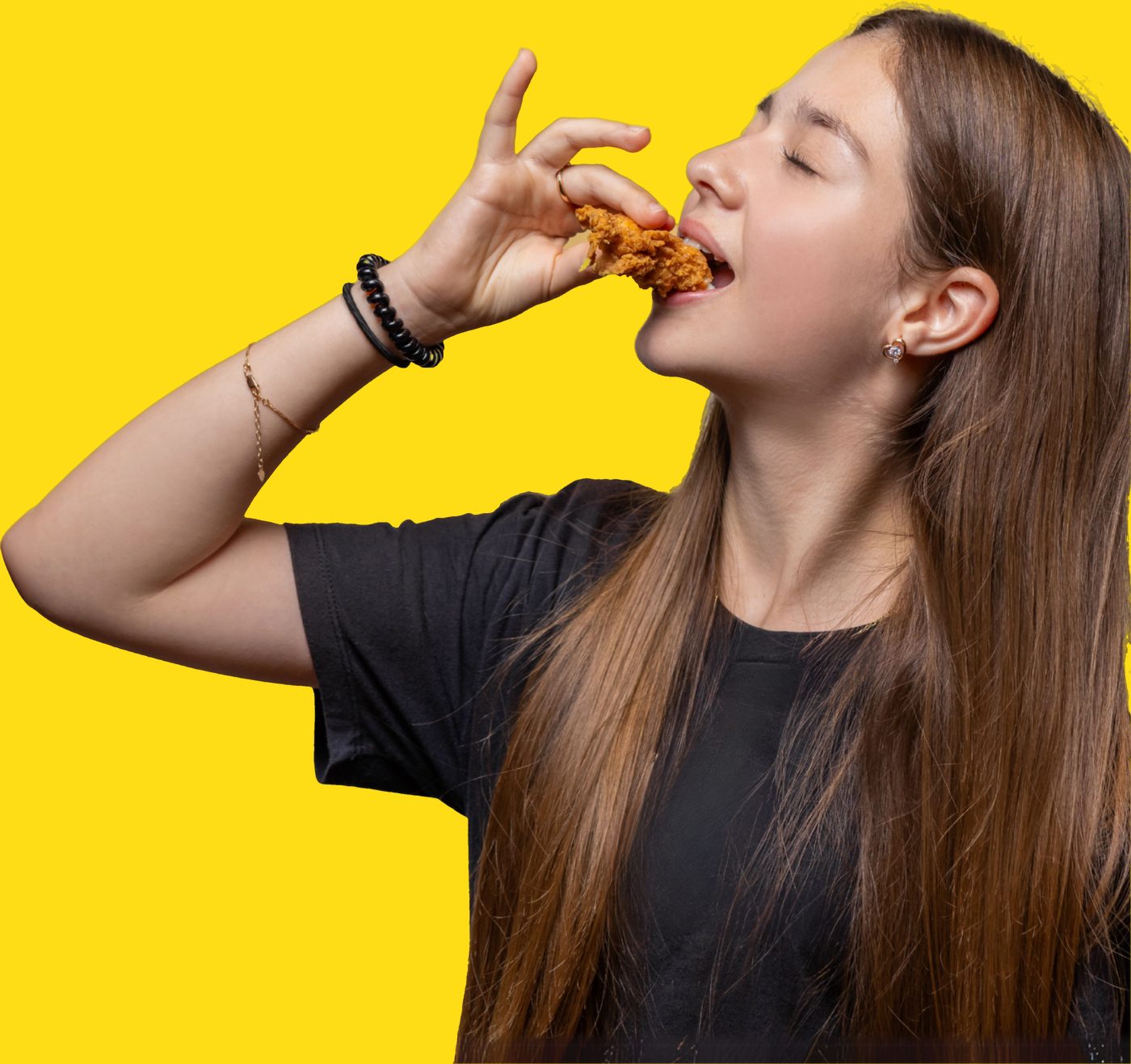 A guest tipping her head back to bite into a hand-breaded Honestly Good chicken finger
