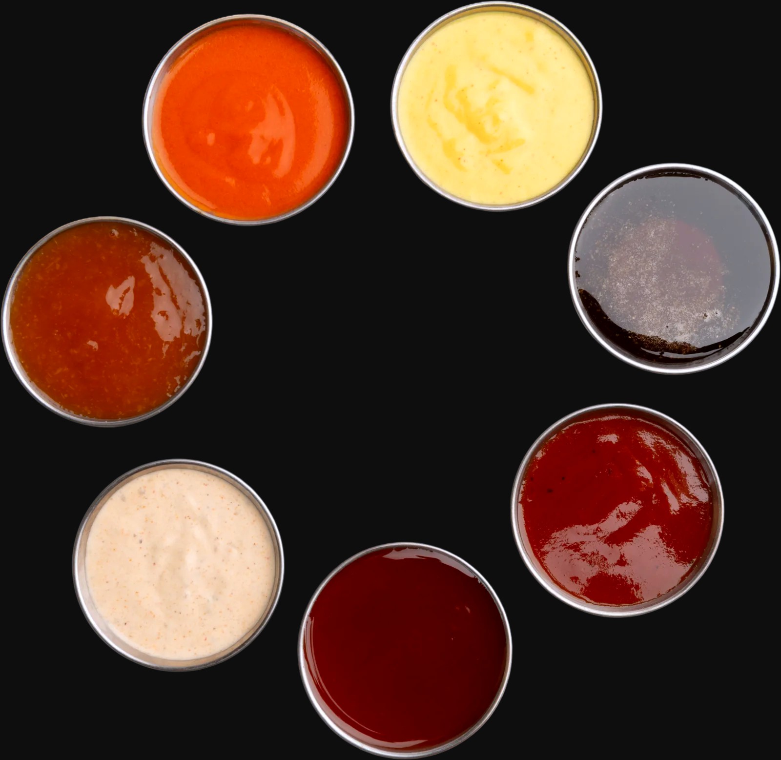 All seven Honestly Good dipping sauces in metal cups, shot from above: buffalo, honey mustard, BBQ, hot and honey, Honestly Good sauce, pleasantly plum and dupe sauce