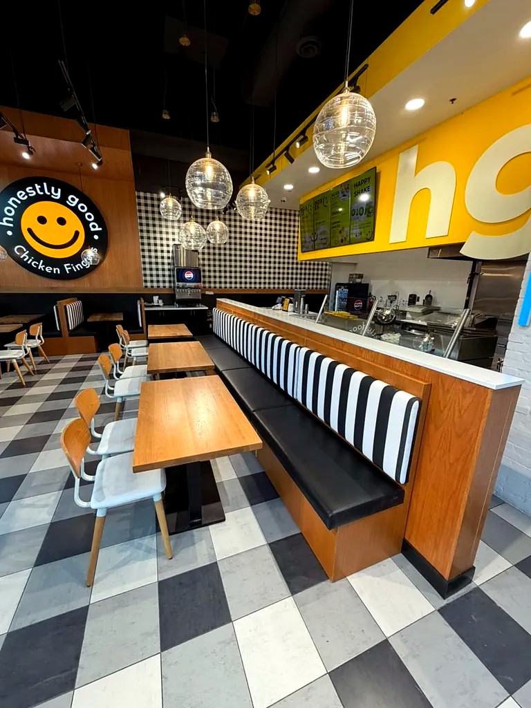 Inside Honestly Good Chicken Fingers at Stockyards: striped banquette seating, wooden tables and a checkerboard floor