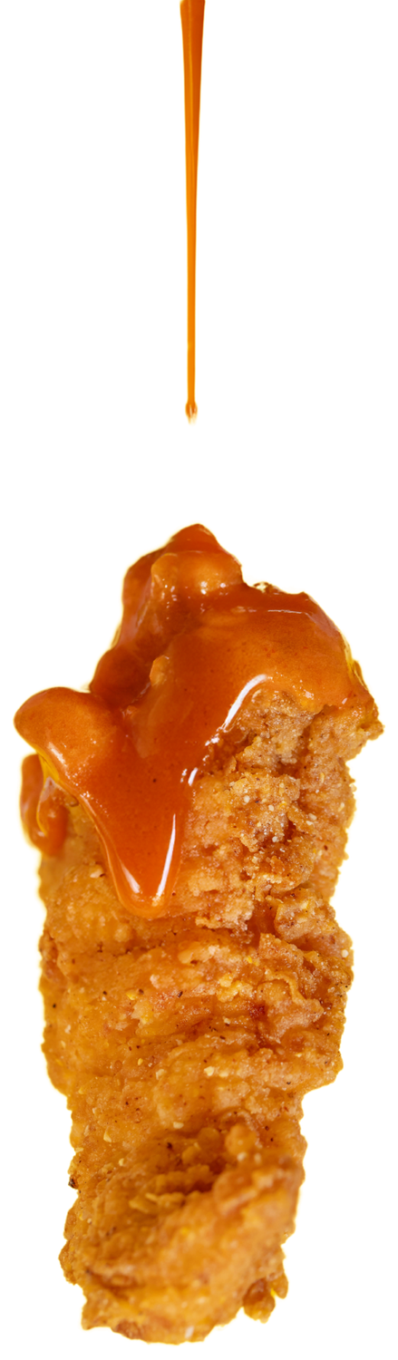 A hand-breaded Honestly Good chicken finger with house sauce pouring over it